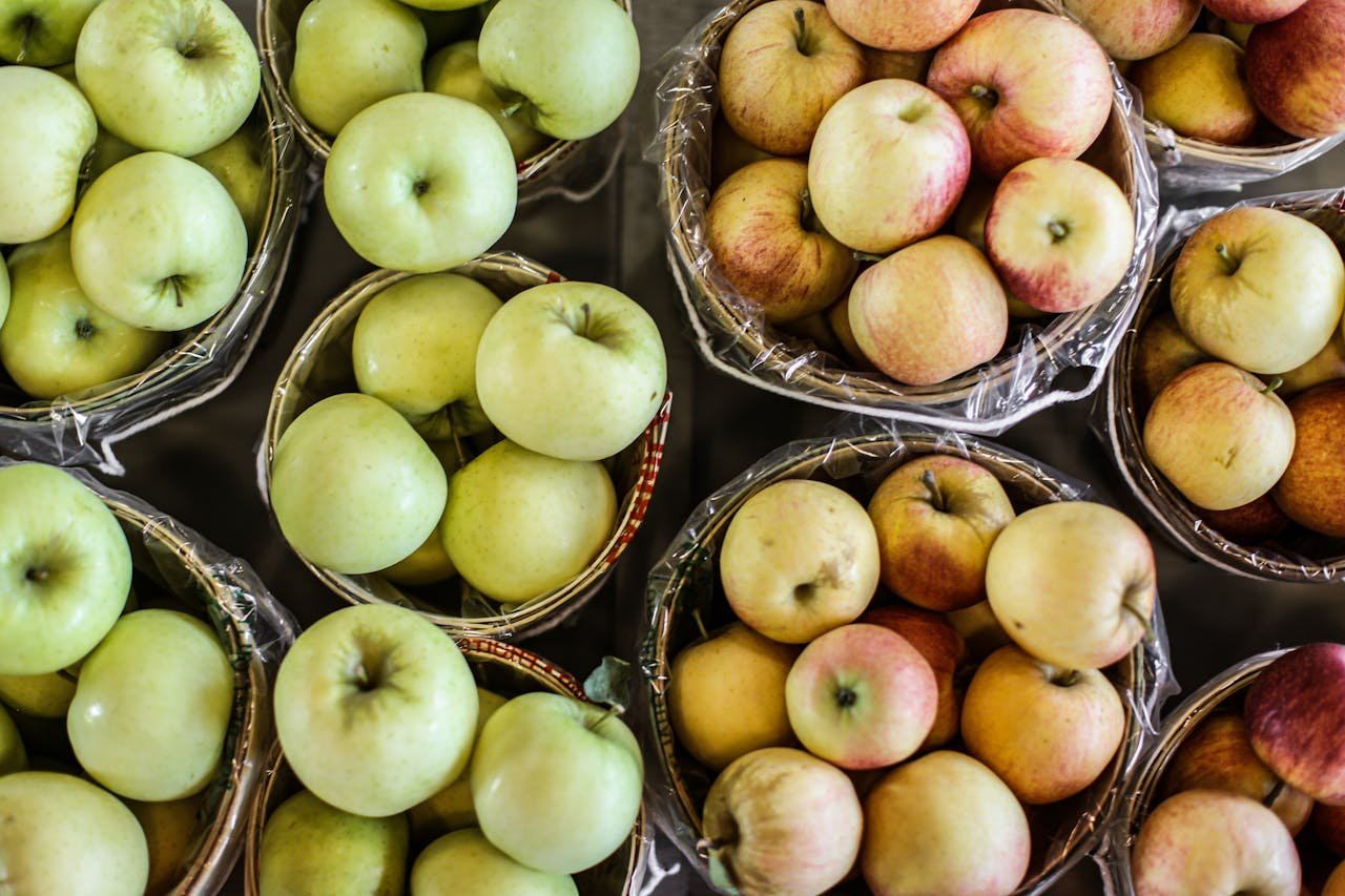 A top view of fresh green and red apples in wicker baskets, showcasing abundance and freshness.